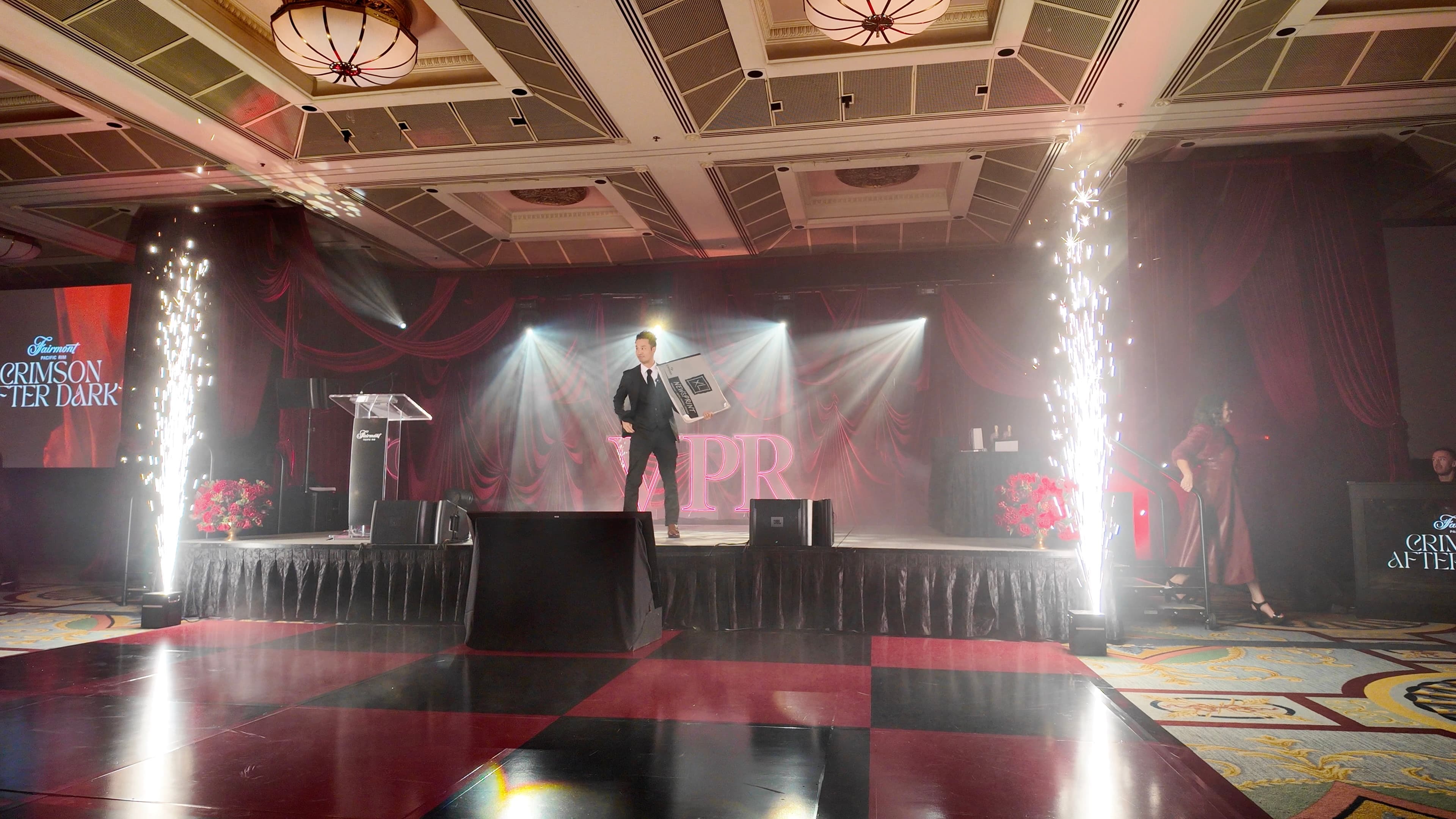 Kel alone on a red-lit ballroom stage set for a hotel staff appreciation party in Vancouver