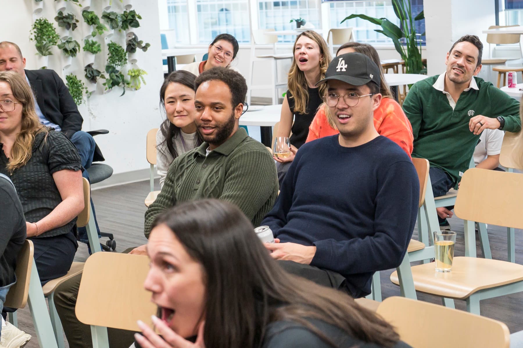 A group of Thinkific employees seated and reacting with surprise during a close-up magic set at their office happy hour