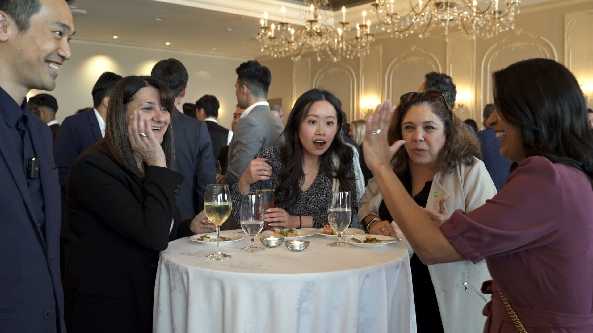 Guests at a cocktail table reacting during close-up magic at a Vancouver company event