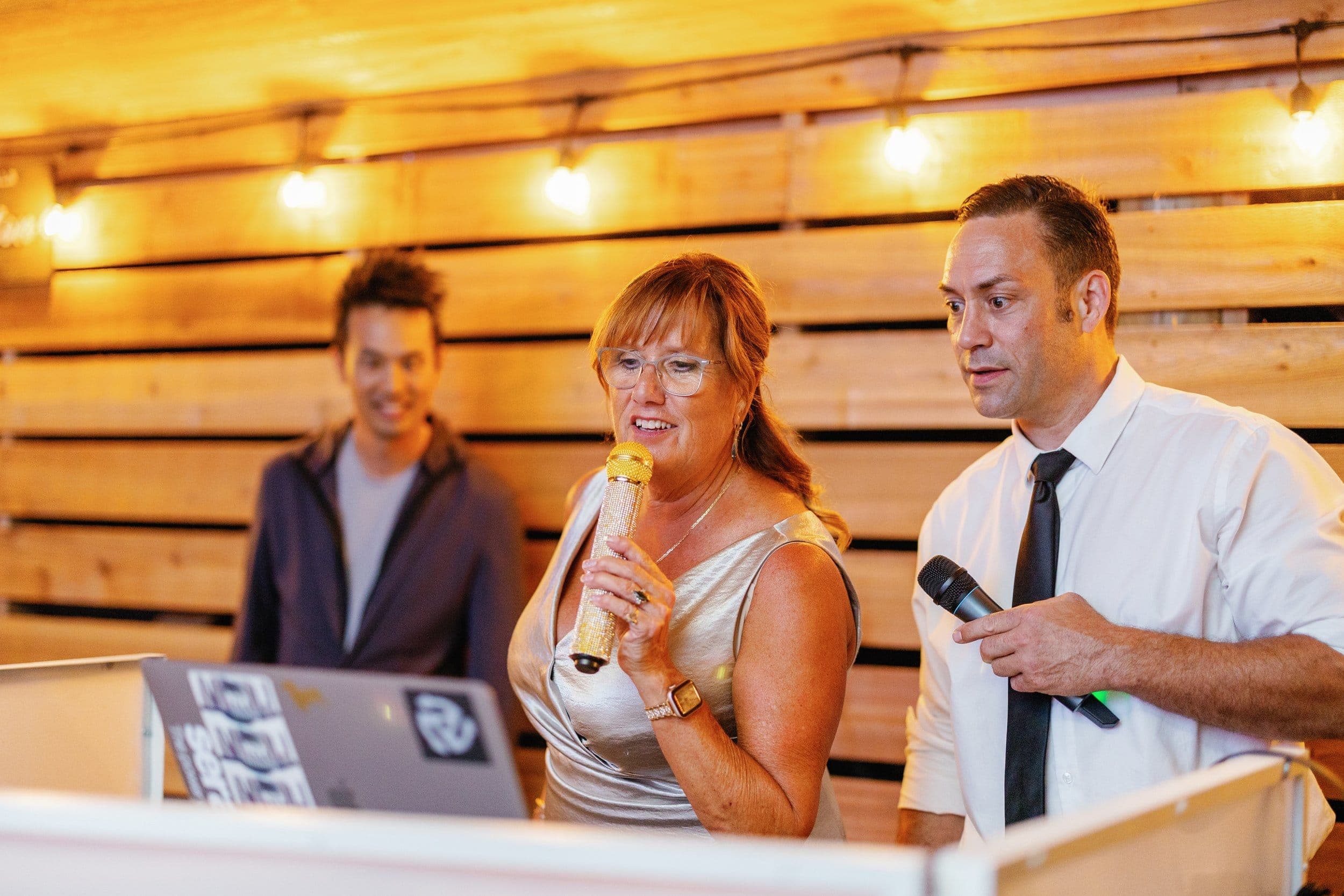 Vancouver MC Mike Oulton with a microphone beside a guest singing at an event
