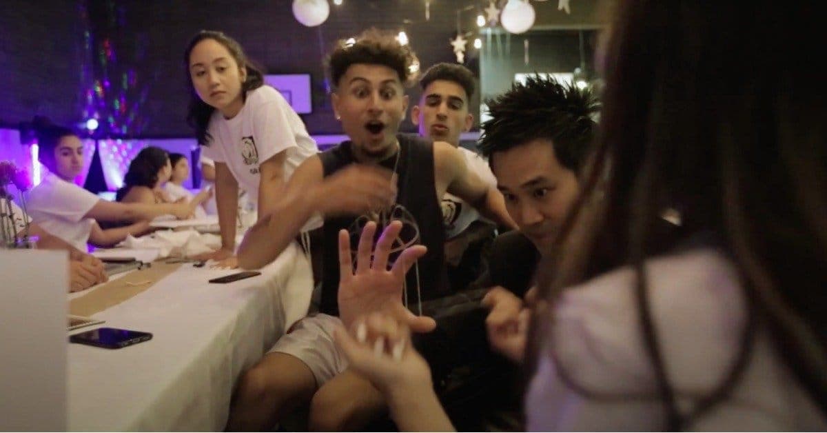 Grad students at a long table reacting in shock to close-up magic at a BC dry grad