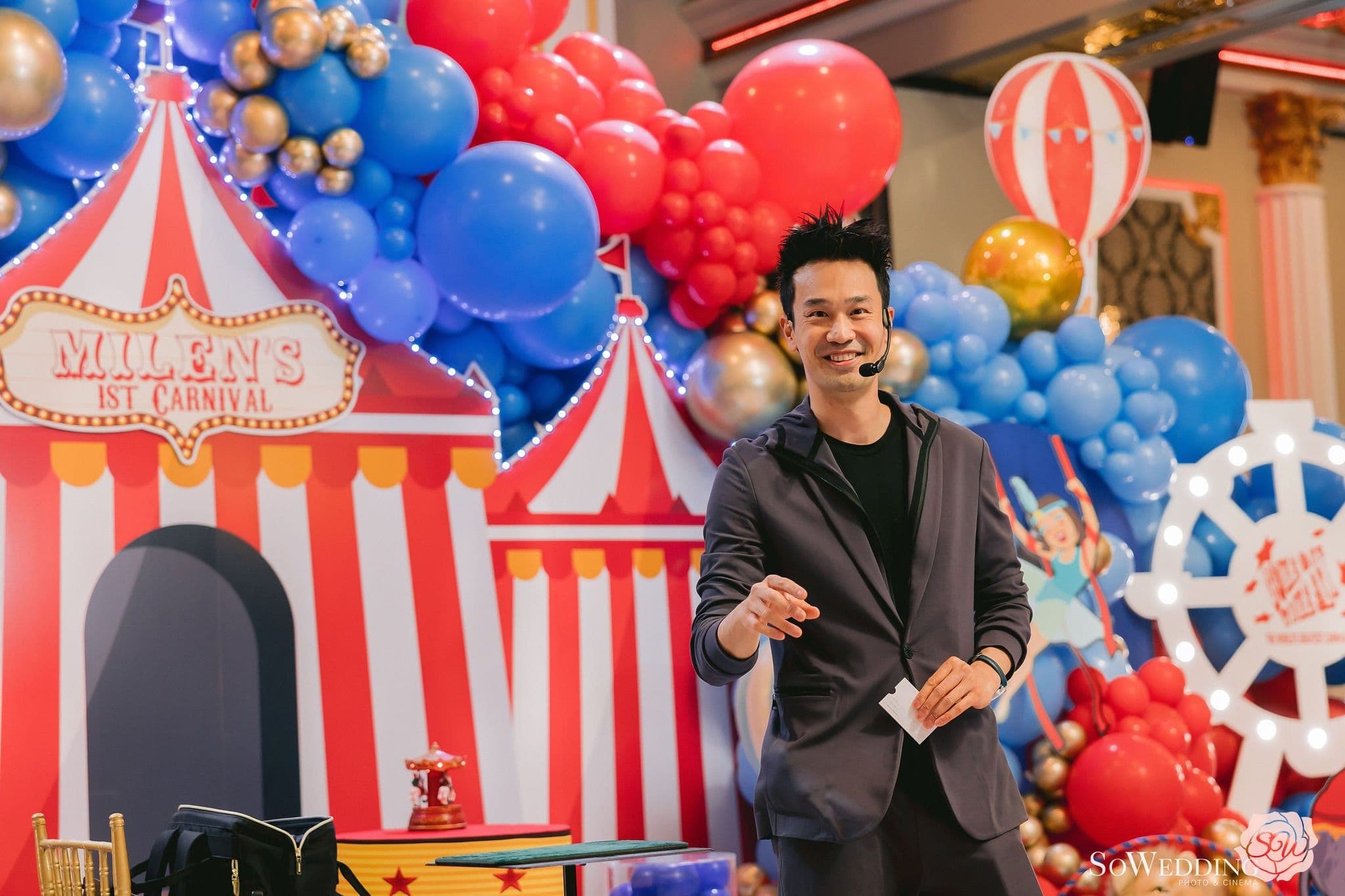 Kel performing in front of a circus-themed balloon display at a child's first birthday party in Vancouver