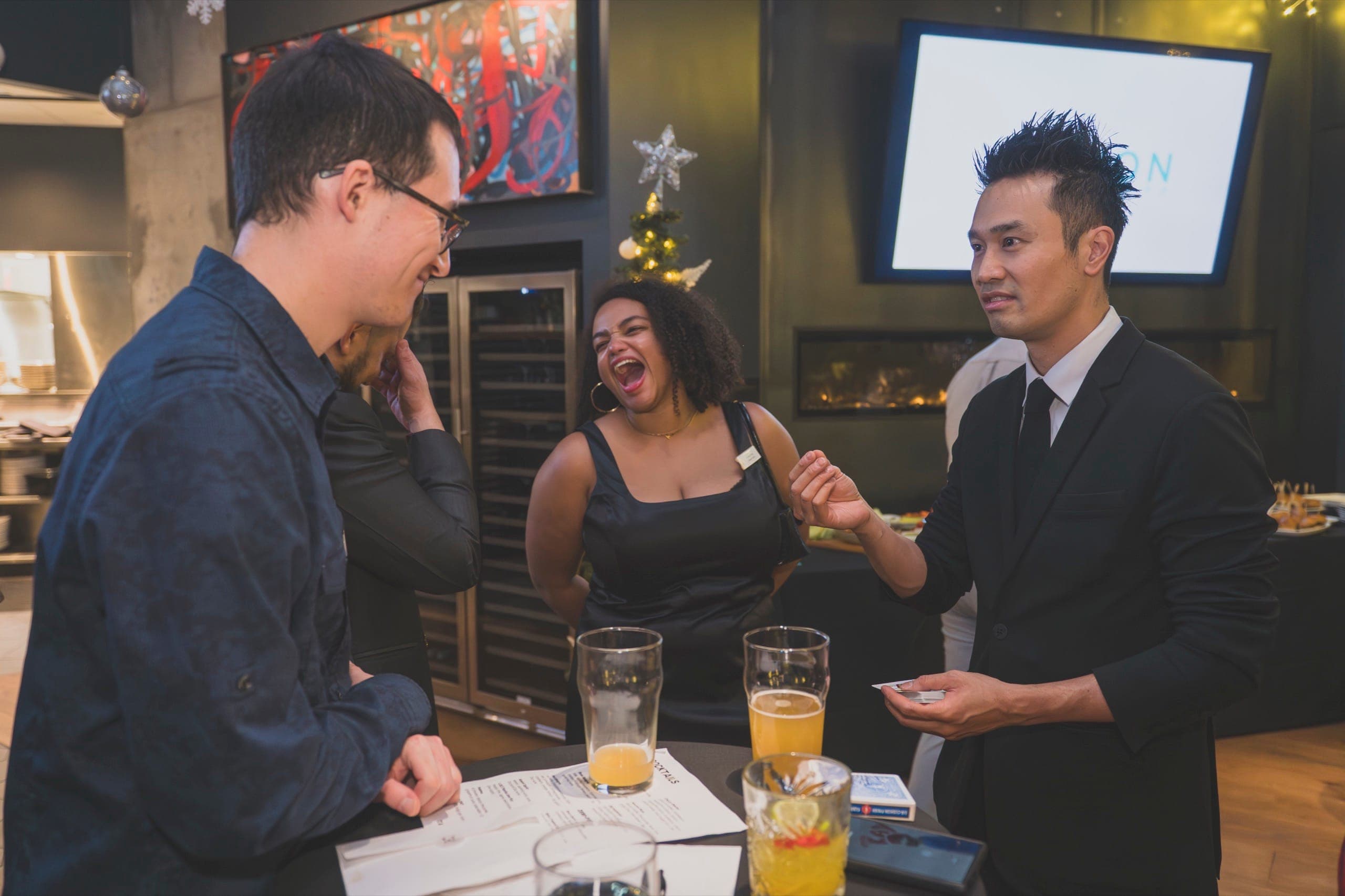 A guest laughing hard during close-up magic at a corporate cocktail hour in Vancouver