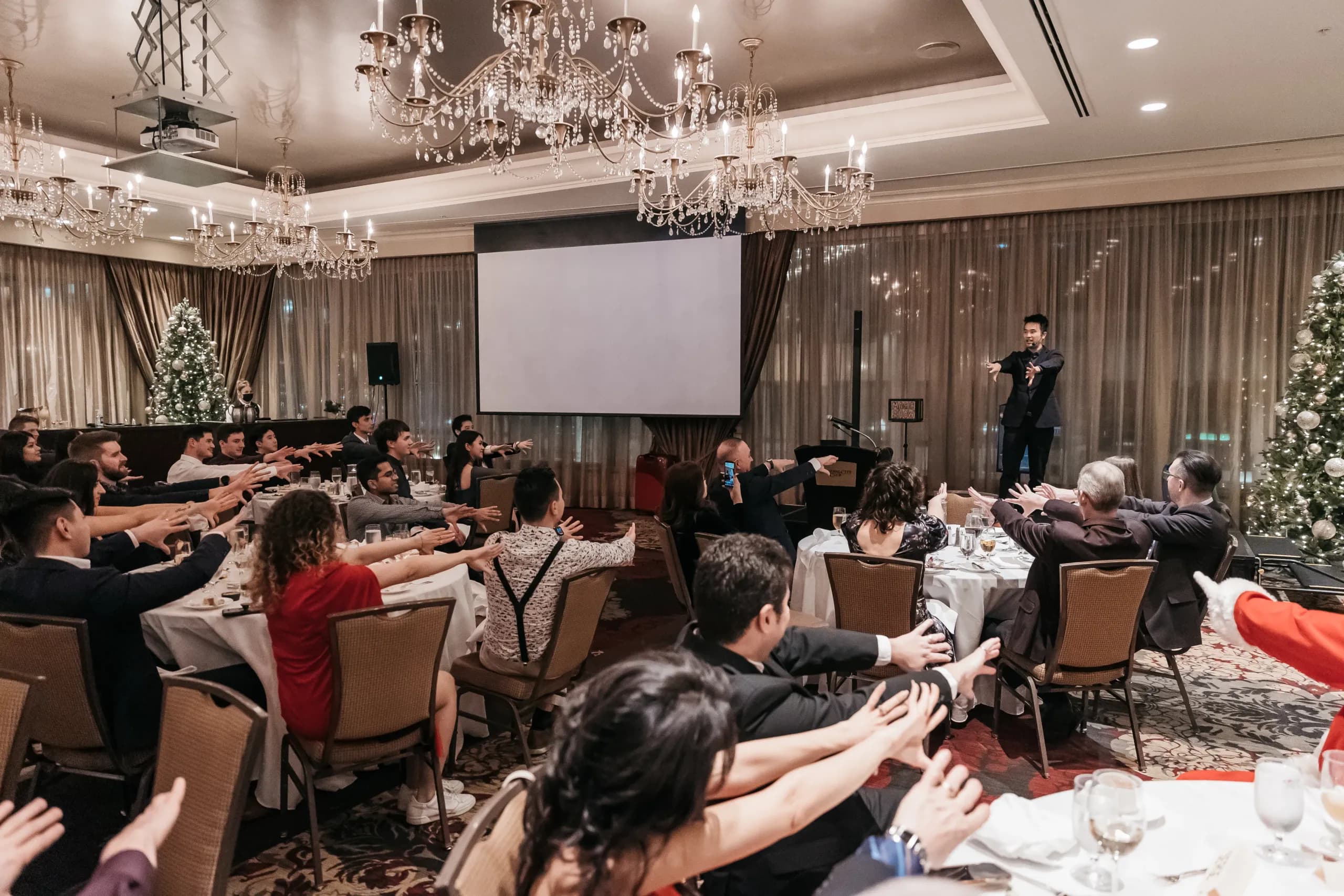 Guests applauding with hands raised at the end of a corporate magic show in Vancouver