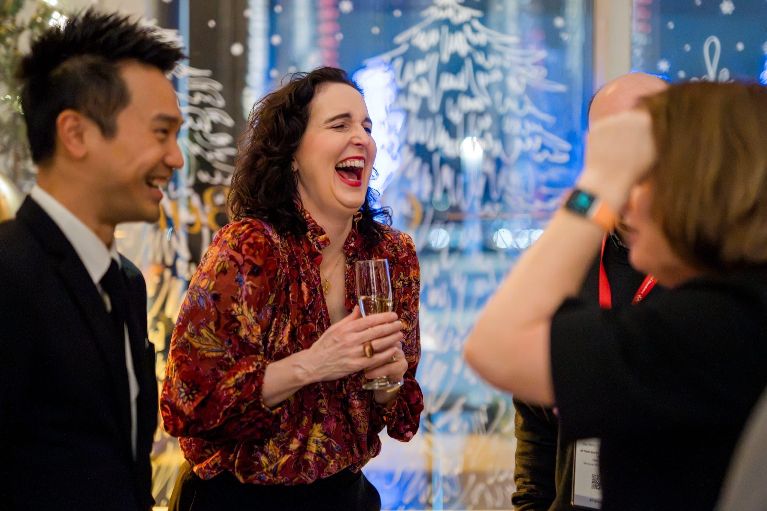 Guests laughing during close-up magic at HUB International's Vancouver holiday party