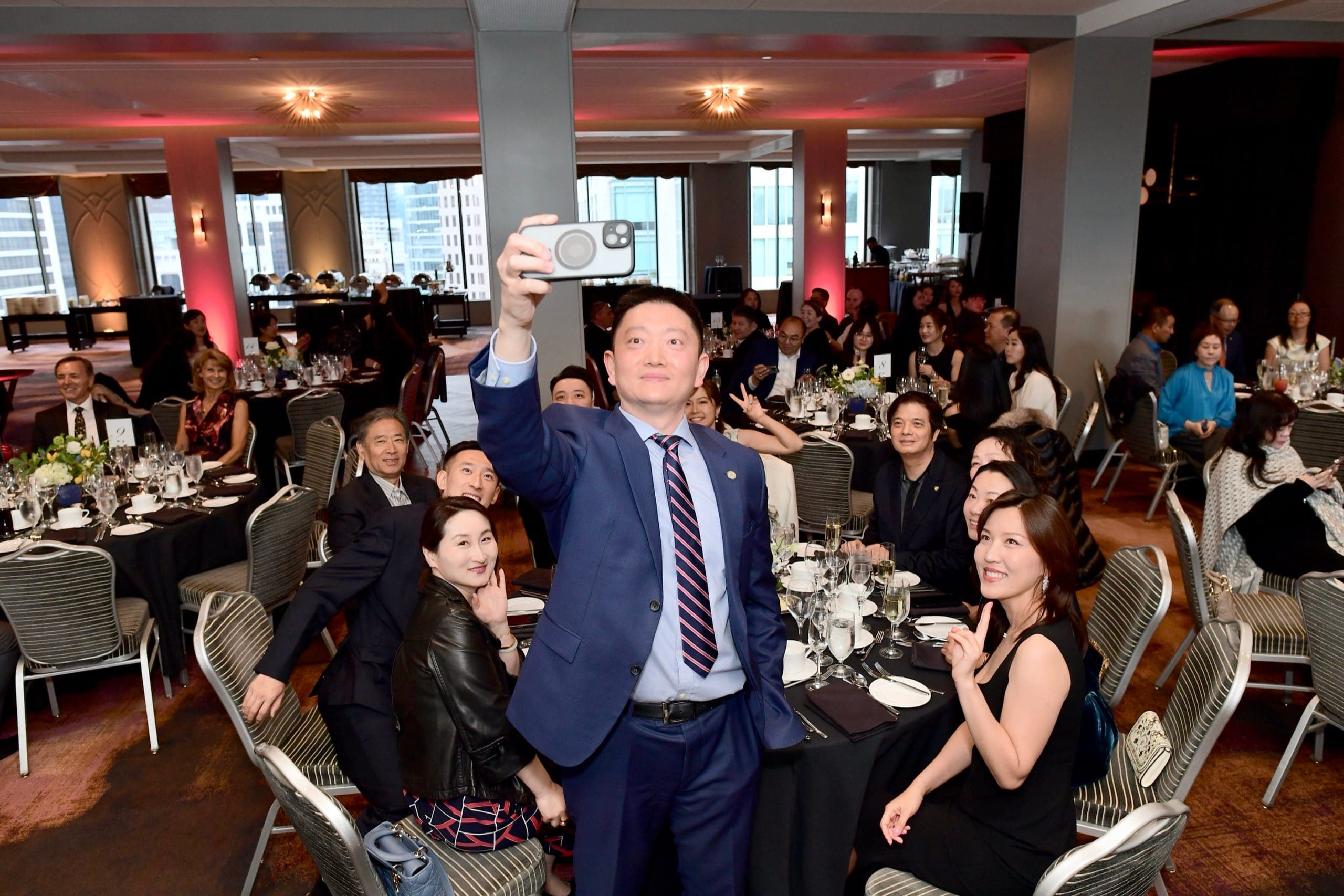 VIP table guests reacting with excitement during a selfie at the Sun Life Excellence Cup banquet in Vancouver