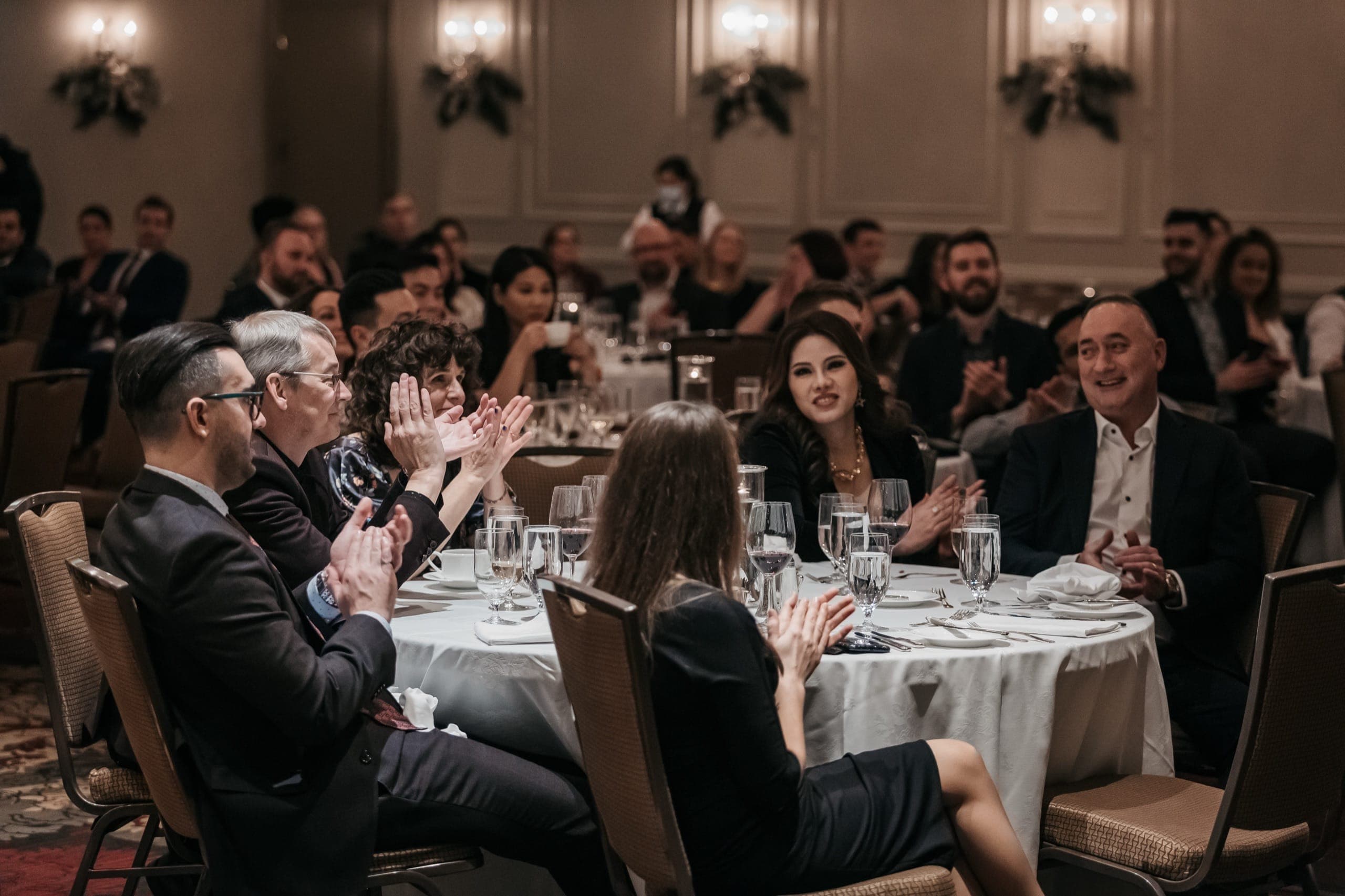 Guests at a Vancouver corporate holiday party applauding at their table during the evening programme