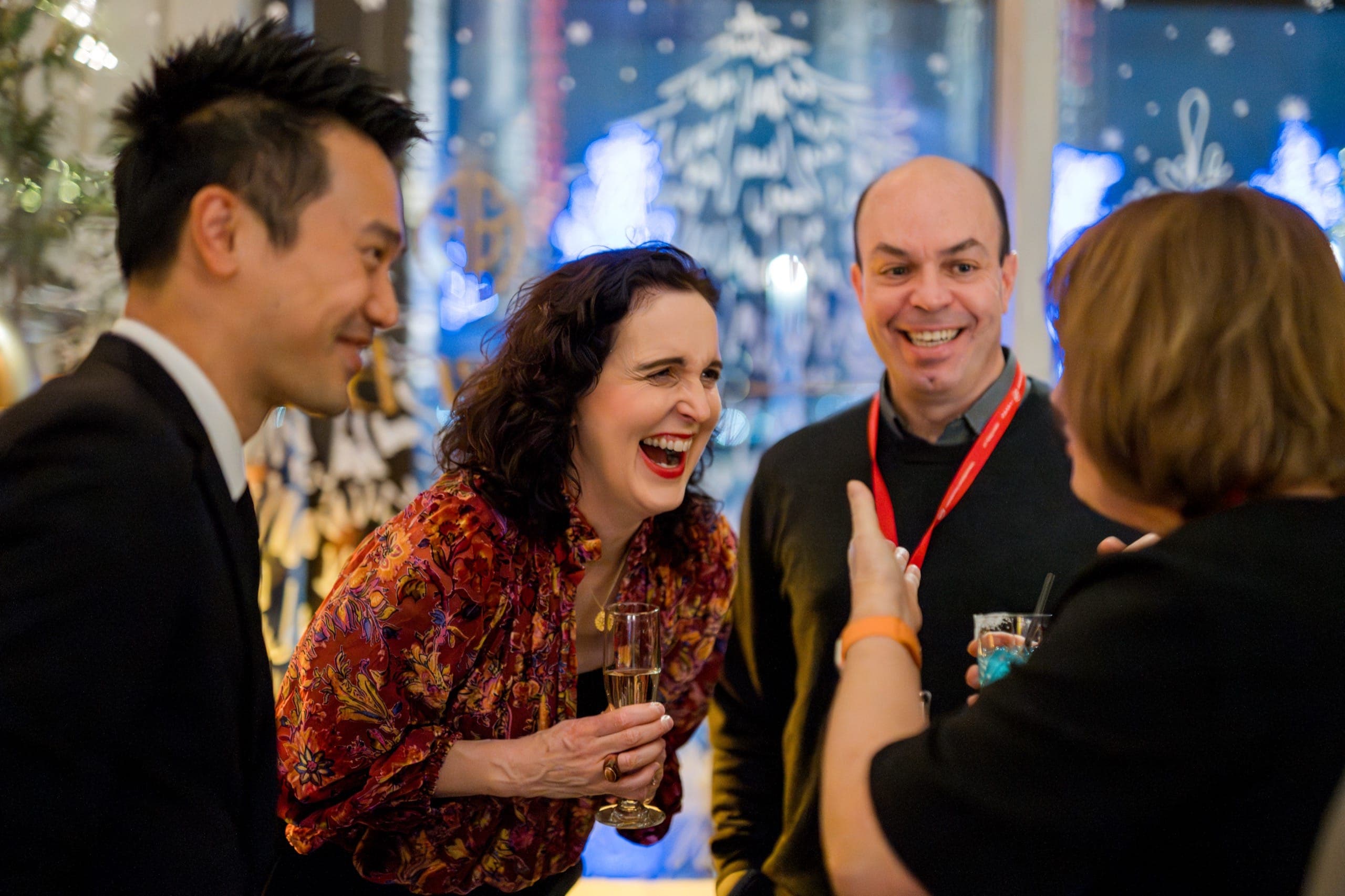 Colleagues laughing together at a festive window during a Vancouver company Christmas party