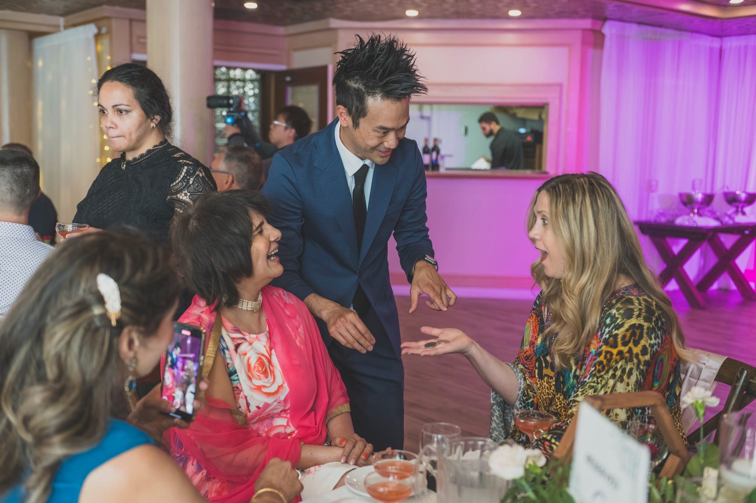 A guest reacting with amazement to a coin trick at a Vancouver wedding cocktail hour
